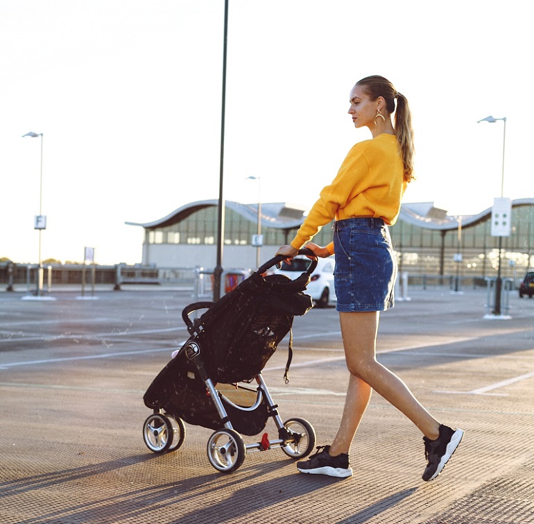 picture of a woman with a baby pram stroller on a parking lot