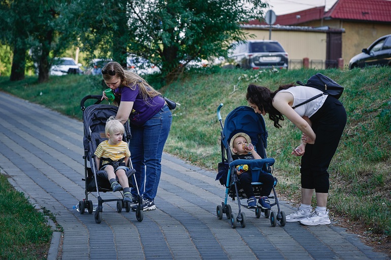 picture of two woman with their kids in pram stroller in the park
