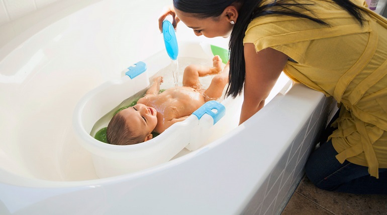 mom giving baby a bath in a baby bathtub 
