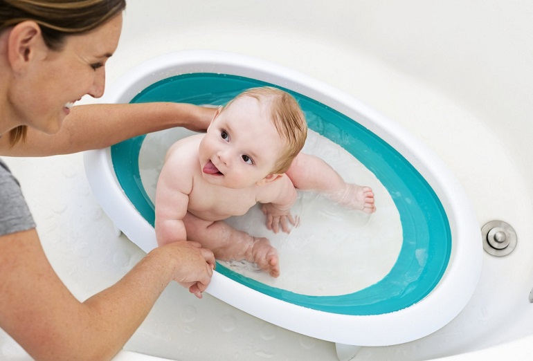 mom bathing baby in little blue bathtub 
