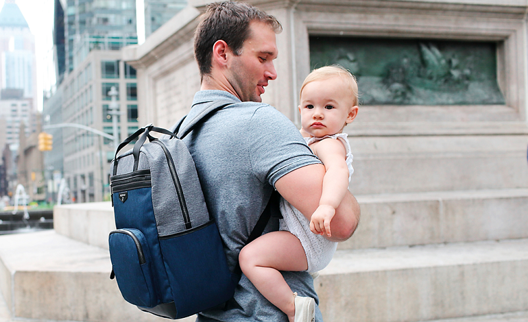 dad with nappy bag carrying his baby in his arms
