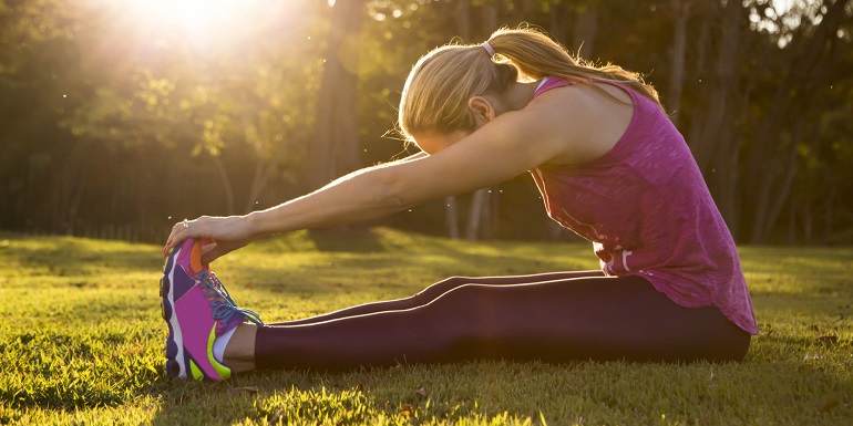 Woman stretching on grass at sunset
