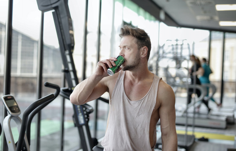 bodybuilder drinking energy drink at the gym